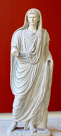 A classical marble statue of a figure standing against a red background, draped in flowing robes, conveying a sense of ancient elegance. The figure holds a spherical object in one hand, symbolizing celestial bodies.