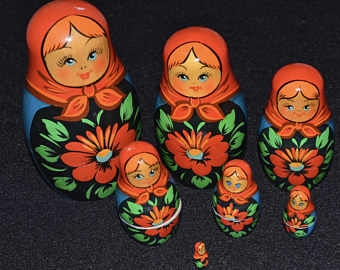 A collection of traditional Russian matryoshka dolls, varying in size with each featuring a painted figure of a woman adorned with floral patterns on a black background.
