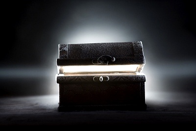 An illuminated ancient tome, stacked on top of another closed book, glows mysteriously under a focused beam of light in a dimly lit environment. The scene suggests the revelation of hidden wisdom or profound secrets.