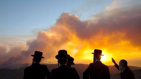 Silhouettes of four individuals wearing top hats observing a brilliant sunset with vibrant orange clouds, possibly discussing celestial phenomena or the Mazzaroth.