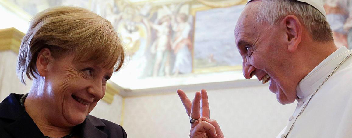 Former German Chancellor Angela Merkel laughs with Pope Francis in a richly decorated room, while the Pope makes a playful victory sign with his fingers.