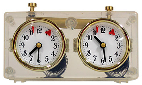 An image of a double clock encased in a transparent body with golden dials and white faces marked with numbers. Each clock is decorated with black minute and hour hands, and a red second hand.