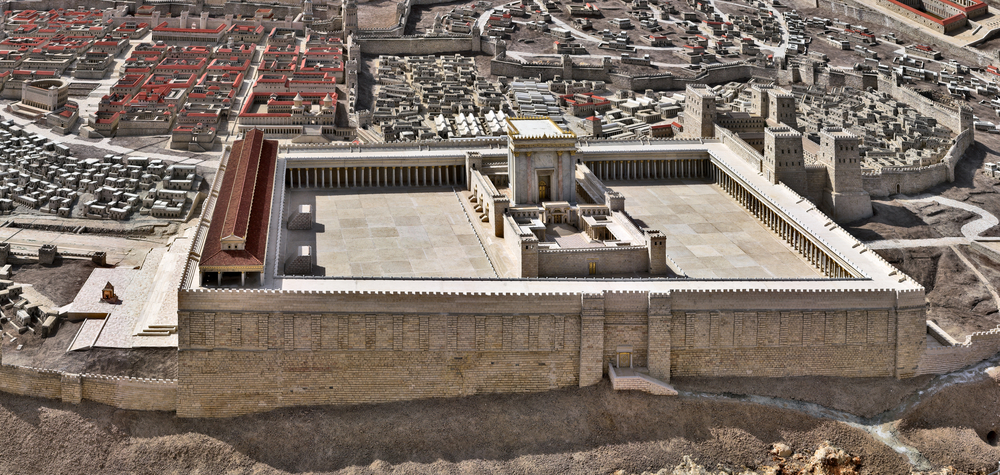 A detailed model representing an ancient temple complex surrounded by a fortified wall, set within a meticulously reconstructed historical cityscape with various structures and streets.