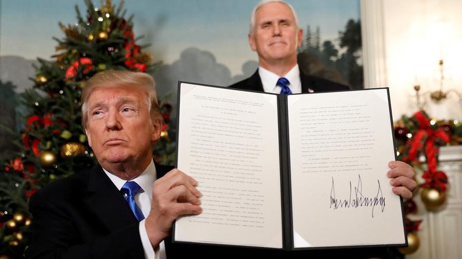 Two men in formal attire in an ornately decorated room with a Christmas tree. One man, sitting, is holding a document towards the camera, another, standing, holds the same document open so both pages are visible.