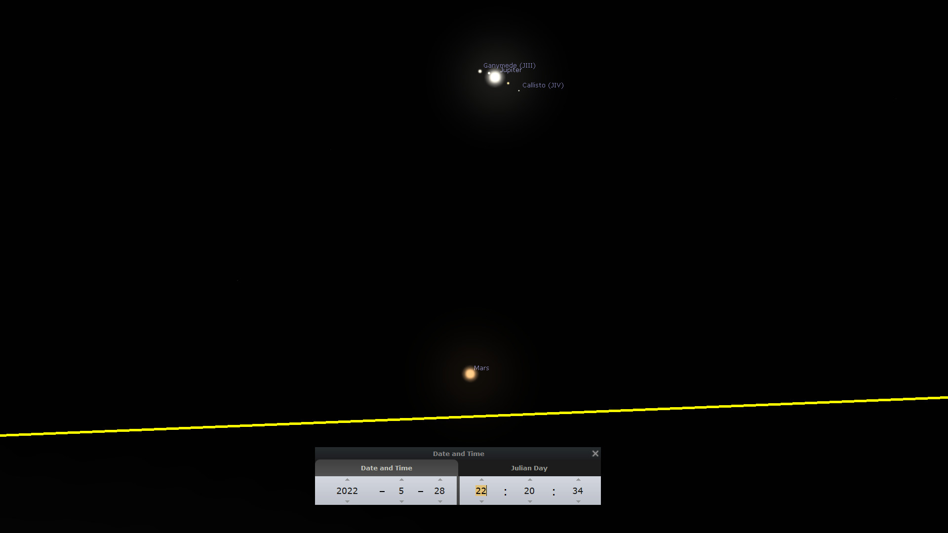 A dark space scene showing bright luminous objects, which include the planet Jupiter and its moons Ganymede and Callisto, with the planet Mars glowing distinctly in the foreground. Below, a yellow horizontal line spans across the frame with a window displaying Date and Time settings.