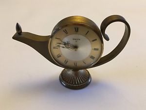 Antique metallic teapot with a built-in clock featuring Roman numerals on the face, and a depiction of a celestial event showing a small comet passing through the Mazzaroth.