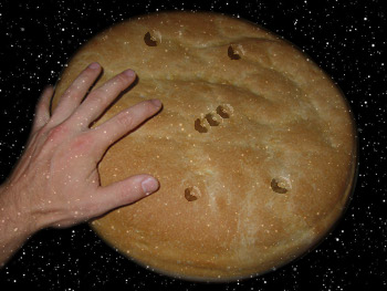 A person's hand touching a flat, round bread against a backdrop of stars, symbolizing a celestial theme inspired by the Mazzaroth.