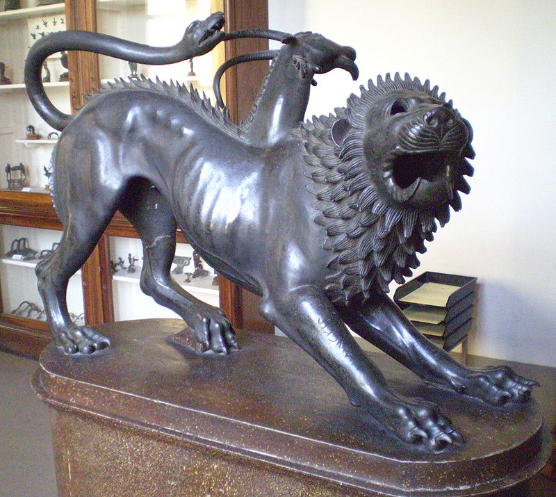 A bronze sculpture of a lion with an ornate mane and the tail of a serpent, positioned on a pedestal. The mythical creature is depicted mid-roar, emphasizing its open mouth and detailed features.