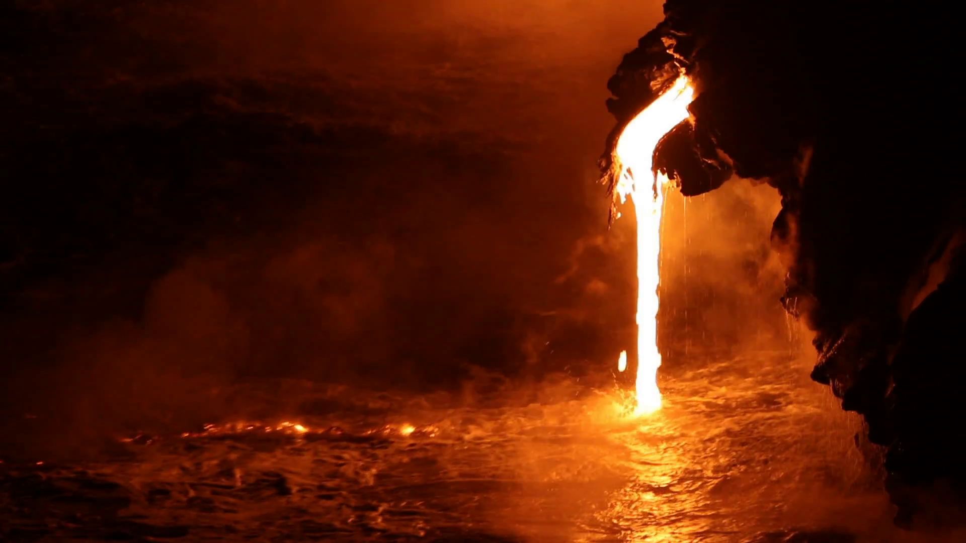 A dynamic and fiery molten lava flow is seen pouring majestically into the ocean, casting an intense orange glow that illuminates the surrounding darkness, against the backdrop of turbulent, misty waves.