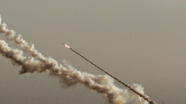 Un cohete asciende contra un cielo neutro, dejando tras de sí una espesa estela de humo que recuerda las trayectorias trazadas por los cuerpos celestes en el firmamento.
