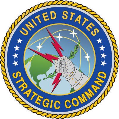 Emblema oficial del Comando Estratégico de los Estados Unidos que presenta un globo terráqueo centrado en América del Norte, superpuesto por un puño blindado que sostiene tres rayos y una rama de olivo, rodeado por una banda azul con 13 estrellas y enmarcado por un borde de cuerda dorada.