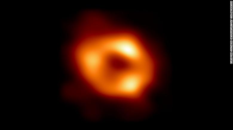 Bild der ersten erfolgreichen hochauflösenden Aufnahme, die das astronomische Phänomen eines Schwarzen Lochs zeigt, das im Kosmos von einem Halo aus leuchtendem Gas umgeben ist.
