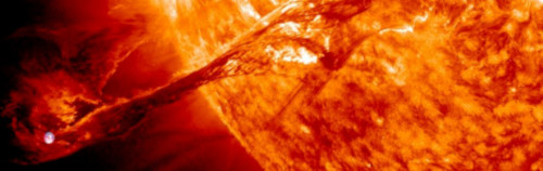 Imagen de primer plano de una llamarada solar que se emite desde la superficie del sol, que muestra una liberación dinámica de plasma en un tono rojo y naranja.