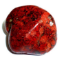 Close-up of a polished red and black gemstone with vivid textures and flecks reflecting light.