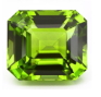 A vibrant green gemstone, rectangular in shape with beveled edges, reflects light brilliantly.