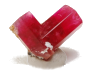 A translucent pink crystal resembling the shape of a heart, placed on a reflective surface with hues of pink and gold.
