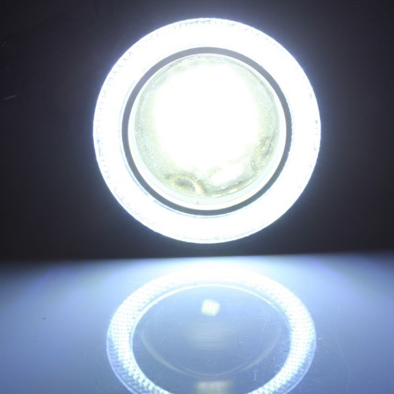 A luminous circular object resembling a celestial body is centrally illuminated with a stark, bright light, surrounded by an opaque circular band with inscriptions, mirrored impeccably on a reflective surface below.