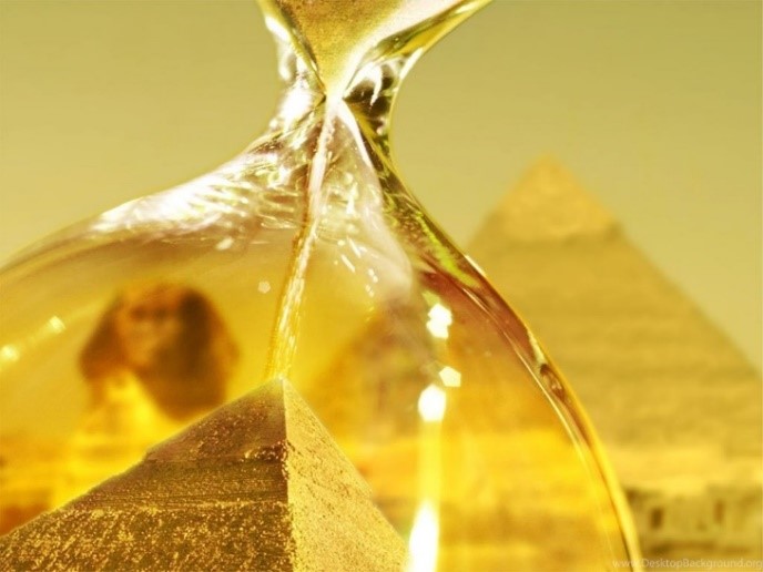 A close-up view of an hourglass with golden sand flowing through its narrow neck, set against a blurred backdrop featuring the ancient Egyptian pyramids and the Sphinx under a warm golden hue.
