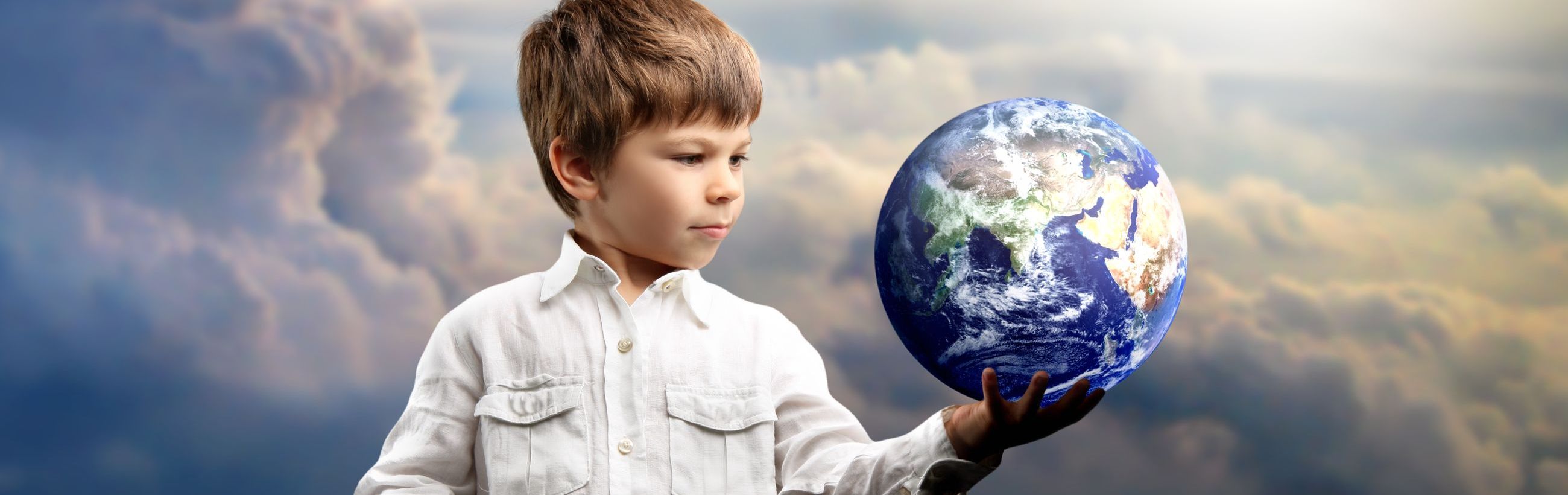 A young boy, dressed in a white shirt, holds a detailed, oversized globe against a backdrop of clouds illuminated by sunlight. The image symbolizes stewardship and the wonders of our planet Earth, as viewed from an astronomical perspective.