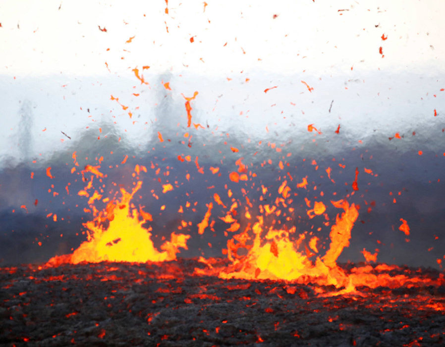 A dynamic geological scene displaying a volcano erupting with vibrant molten lava spewing into the air against a hazy background.