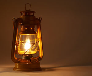 A warm, glowing oil lantern illuminates a soft beige background, reminiscent of guiding lights used under the stars of the Mazzaroth.