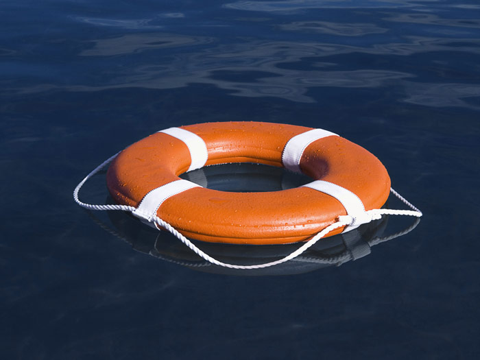Un aro salvavidas naranja con marcas blancas flotando en aguas tranquilas de color azul oscuro.