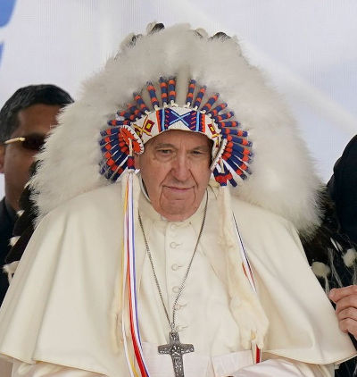 A man dressed in traditional Western religious attire adorned with a large, colorful feathered headdress featuring celestial symbols.