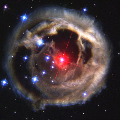 A stunning image of a celestial nebula characterized by a luminous central star encircled by intricate layers of gas and dust, emitting a variety of radiant colors against the backdrop of outer space.