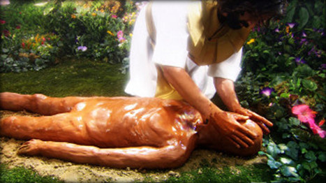 A depiction of a man with shoulder-length hair dressed in a light-colored robe, kneeling in a lush garden next to a figure lying on the ground, who appears to be made entirely of clay. The man is gently touching the clay figure's head, surrounded by vibrant flowers.