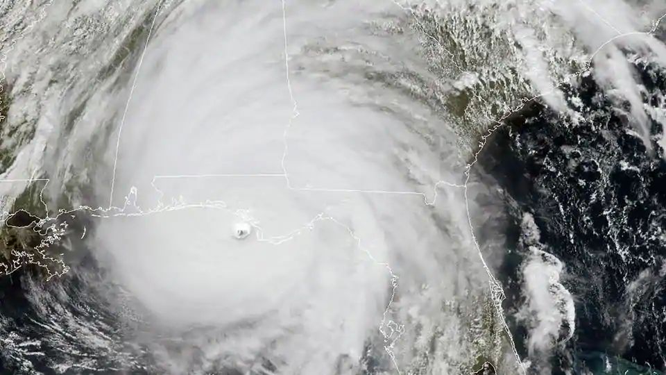 Satellite view of a large hurricane centered over the Gulf of Mexico with its spiral bands extending across multiple states, displaying the vast scale and power of atmospheric phenomena.