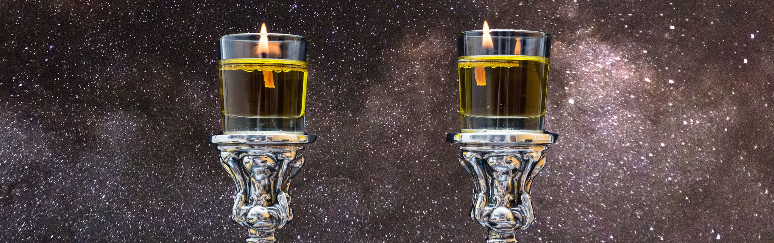 Two ornate silver candle holders featuring lit candles set against a backdrop of a densely star-studded sky. The candles reflect a golden light, contributing to a serene cosmic setting.