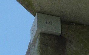 Close-up view of a stone block numbered 14, mounted high on a gray structure under a clear blue sky, potentially part of an installation related to the study of celestial movements.