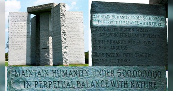 Image of a large gray stone monument resembling an ancient megalithic structure, under a clear blue sky. The monument features various inscriptions in English on slabs, promoting concepts about maintaining humanity's balance with nature and other philosophical statements.