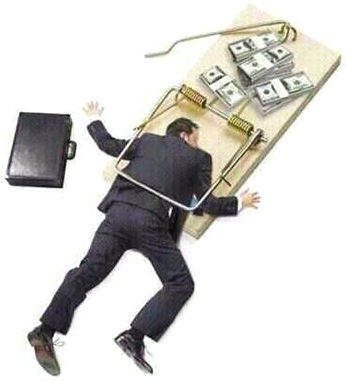A man in a dark suit and shoes lies face-down, seemingly immobilized on a large mousetrap. The trap is baited with stacks of dollar bills, alongside a briefcase and a rope tied to the triggering mechanism.