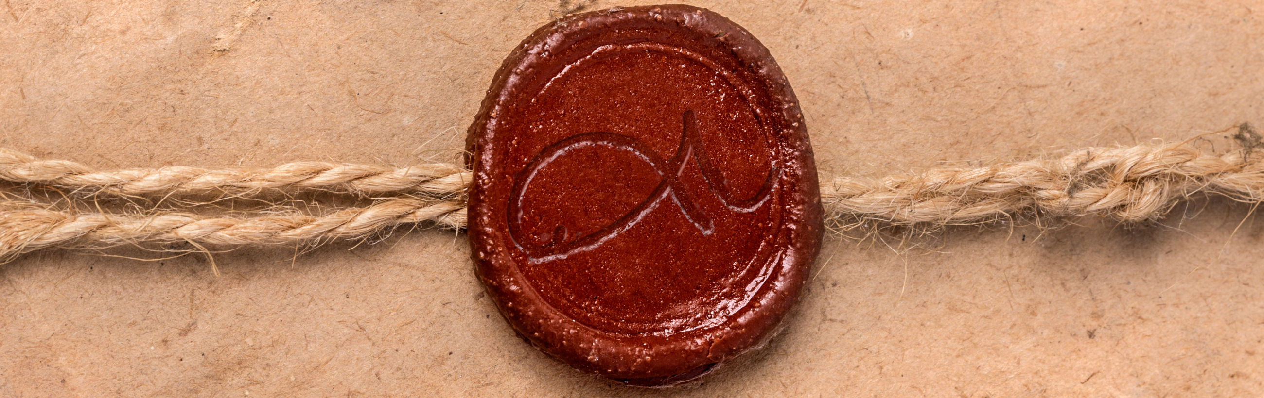 Imagen de primer plano de un sello de cera roja impreso con un símbolo del Mazzaroth, fijado a un documento asegurado con un cordel sobre un fondo de papel texturizado.