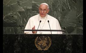A man in religious attire speaks at a podium bearing the United Nations logo.