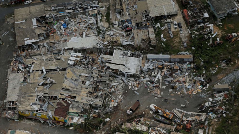 Aerial view of an extensive area of devastation where multiple buildings are severely damaged with debris scattered across the landscape.