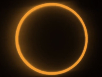 A striking celestial event displaying a solar eclipse, where the moon completely covers the sun, leaving only a glowing ring of sunlight visible against a dark backdrop.