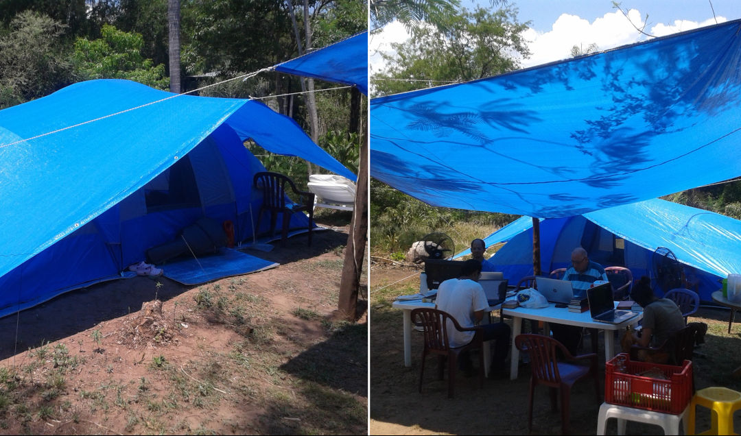 A series of blue tarpaulin shelters in a sunny outdoor setting. The first image shows a tarp sheltering a blue camping tent in a wooded area. The second image includes several people working under a large tarp stretched overhead, with computers set up on plastic tables, blending technology with nature.