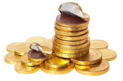 A stack of golden coins adorned with chocolate coins wrapped in silver foil, suggesting themes of wealth and indulgence.
